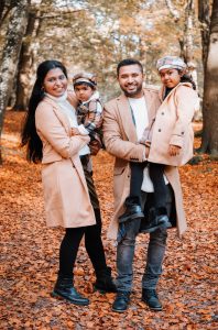 Family of four laughing holding their daughters in an autumnal wood