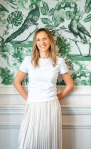 Image of a lady standing against the wall smiling