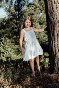 Young Girl at golden hour peeping around a tree