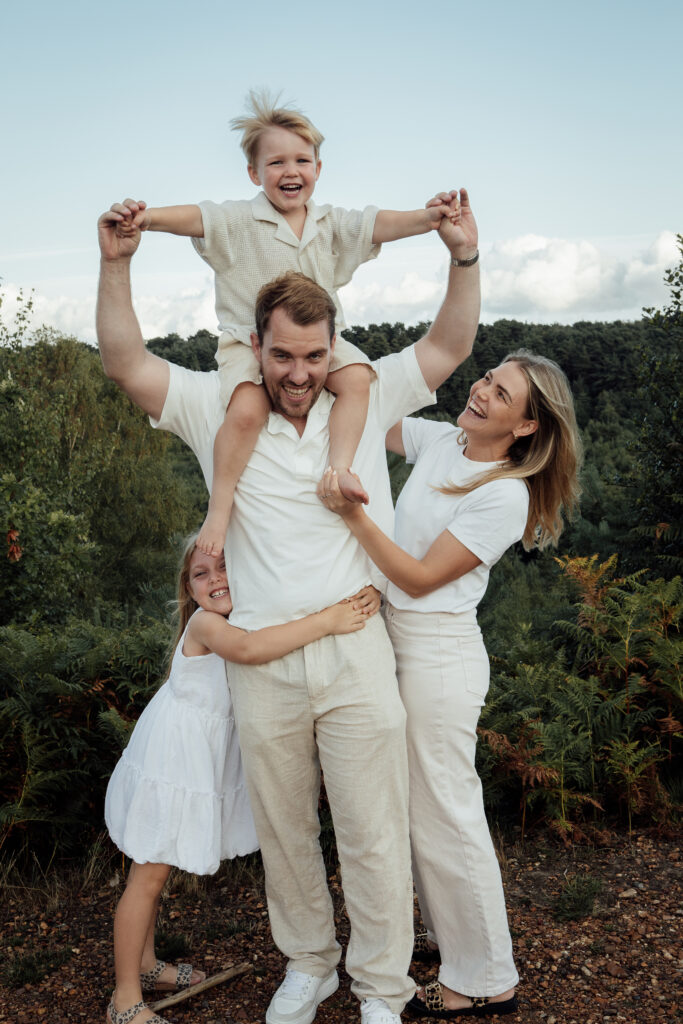 Golden Hour photograph of a family giving cuddling and giving a shoulder carry to their son
