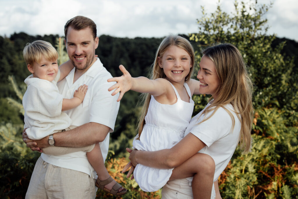 Great natural photo of a couple holding their children having fun at golden hour