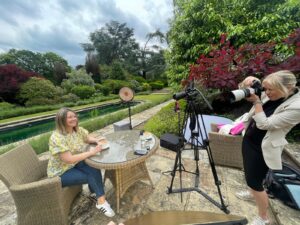Behind the scenes shot of a lady sitting have a coffee in the gardens of the royal berkshire hotel with Debbie Hare photography taking the photo.