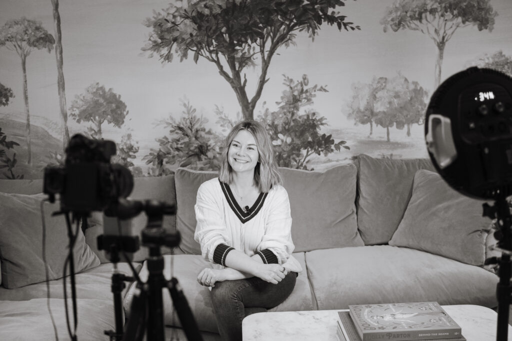 Behind the scenes photograph of Dr Gemma Roberts sitting on a sofa being filmed.
