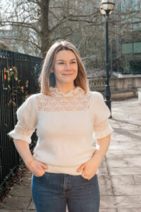 Personal branding photo of Dr Gemma Roberts walking along a city street near the roseate hotel reading.