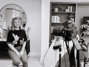 Black and White behind the scenes image of a lady on a photoshoot showing a side angle and camera on a tripod.