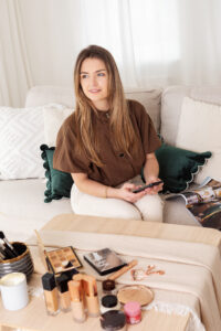 Image of Make-up artist on a phone sitting on a white sofa
