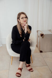 Lady sitting in a studio with her hand on her chin - a thoughtful moment.